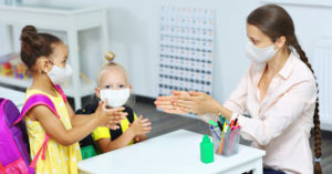 Children and teacher in classroom washing hands