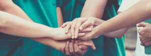 medical professionals put their hands together in a pledge
